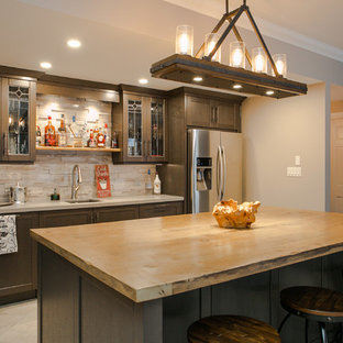 トロントの大きいラスティックスタイルのおしゃれな着席型バー (アンダーカウンターシンク、落し込みパネル扉のキャビネット、濃色木目調キャビネット、クオーツストーンカウンター、グレーのキッチンパネル、大理石の床、磁器タイルの床、グレーの床、グレーのキッチンカウンター) の写真