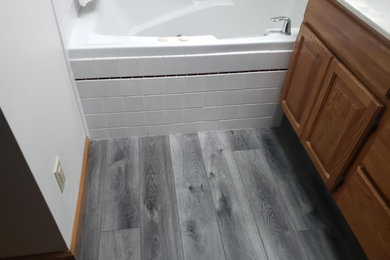 Example of a mid-sized classic master white tile and porcelain tile medium tone wood floor and gray floor alcove bathtub design in Indianapolis with raised-panel cabinets, medium tone wood cabinets, gray walls, an undermount sink, granite countertops and gray countertops