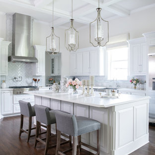 Klassische Küche mit Landhausspüle, profilierten Schrankfronten, weißen Schränken, Küchenrückwand in Grau, Küchengeräten aus Edelstahl, dunklem Holzboden, Kücheninsel, braunem Boden und weißer Arbeitsplatte in Dallas