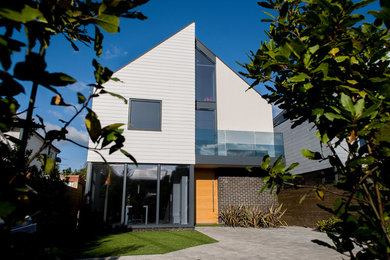Inspiration for a medium sized and white contemporary house exterior in Dorset with three floors, concrete fibreboard cladding and a pitched roof.