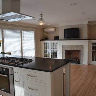 Open concept kitchen - mid-sized modern single-wall light wood floor open concept kitchen idea in Minneapolis with a farmhouse sink, shaker cabinets, white cabinets, soapstone countertops, gray backsplash, subway tile backsplash, stainless steel appliances and an island