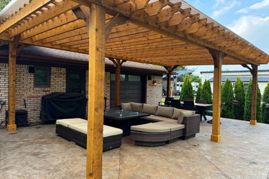Example of a large minimalist backyard stamped concrete patio design in Detroit with a bbq area and a pergola