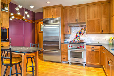 Elegant l-shaped light wood floor enclosed kitchen photo in Other with an undermount sink, shaker cabinets, medium tone wood cabinets, multicolored backsplash, subway tile backsplash, stainless steel appliances and a peninsula
