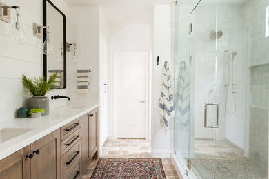 Photo of a large country master wet room bathroom in San Diego with shaker cabinets, dark wood cabinets, gray tile, white walls, an undermount sink, brown floor, a hinged shower door, travertine floors, quartzite benchtops and white benchtops.