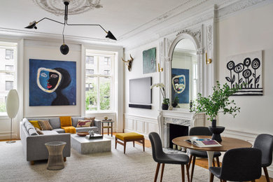 Large trendy loft-style medium tone wood floor, brown floor, exposed beam and wainscoting living room photo in New York with white walls, a standard fireplace and a stone fireplace