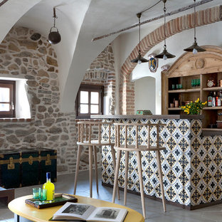 中サイズの地中海スタイルのおしゃれな着席型バー (中間色木目調キャビネット、木材カウンター、セラミックタイルの床、グレーの床、茶色いキッチンカウンター) の写真