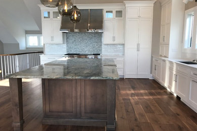 Example of a large transitional l-shaped medium tone wood floor open concept kitchen design in Philadelphia with an undermount sink, shaker cabinets, white cabinets, quartzite countertops, white backsplash, porcelain backsplash, stainless steel appliances and an island
