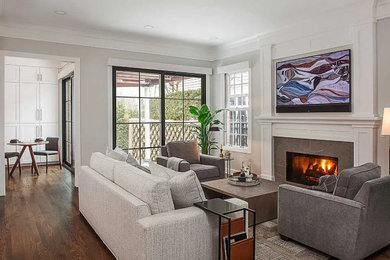 Mid-sized trendy enclosed brown floor and medium tone wood floor living room photo in Detroit with gray walls, a standard fireplace, a stone fireplace and a wall-mounted tv