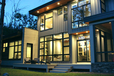 This is an example of a large contemporary two-storey grey exterior in Boston with mixed siding and a flat roof.