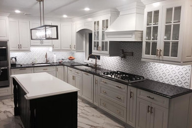 Large elegant l-shaped porcelain tile eat-in kitchen photo in New York with an undermount sink, white cabinets, granite countertops, white backsplash, glass tile backsplash, stainless steel appliances and an island