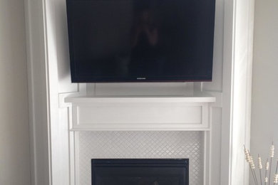 Inspiration for a small transitional beige floor and carpeted family room remodel in Calgary with a corner fireplace, a wall-mounted tv, gray walls and a tile fireplace