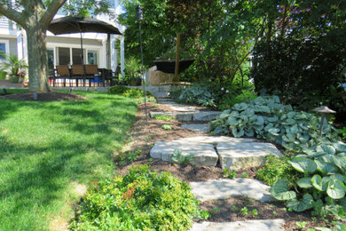 Traditional backyard formal garden in Chicago with natural stone pavers and with path.