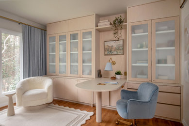 Transitional built-in desk medium tone wood floor and brown floor home office photo in Raleigh with white walls