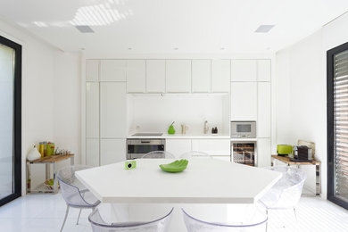 Design ideas for a contemporary single-wall separate kitchen in Paris with an undermount sink, recessed-panel cabinets, white cabinets, solid surface benchtops, white splashback, stainless steel appliances, ceramic floors and white floor.