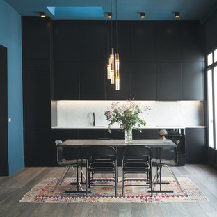 Modelo de cocina lineal, actual, grande, abierta, con fregadero bajoencimera, armarios con rebordes decorativos, puertas de armario negras, encimera de mármol, salpicadero blanco, salpicadero de piedra caliza, electrodomésticos negros, suelo de madera oscura y suelo gris