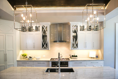 Example of a mid-sized transitional l-shaped kitchen design in Kansas City with an undermount sink, shaker cabinets, white cabinets, marble countertops, white backsplash, glass tile backsplash, stainless steel appliances and an island