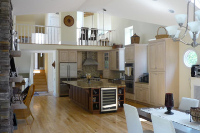 Open concept kitchen - mid-sized contemporary l-shaped light wood floor and multicolored floor open concept kitchen idea in New York with an undermount sink, raised-panel cabinets, distressed cabinets, granite countertops, brown backsplash, glass tile backsplash, stainless steel appliances, an island and brown countertops