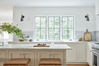 Inspiration for a large timeless l-shaped medium tone wood floor and brown floor kitchen remodel in Boston with an undermount sink, shaker cabinets, white cabinets, marble countertops, gray backsplash, marble backsplash, stainless steel appliances, an island and gray countertops