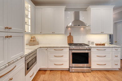 Eat-in kitchen - mid-sized transitional u-shaped medium tone wood floor and brown floor eat-in kitchen idea in Atlanta with an undermount sink, shaker cabinets, white cabinets, quartzite countertops, white backsplash, stainless steel appliances, a peninsula, white countertops and subway tile backsplash