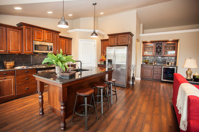 Mid-sized elegant l-shaped dark wood floor eat-in kitchen photo in Milwaukee with an undermount sink, raised-panel cabinets, medium tone wood cabinets, granite countertops, metallic backsplash, ceramic backsplash, stainless steel appliances and an island