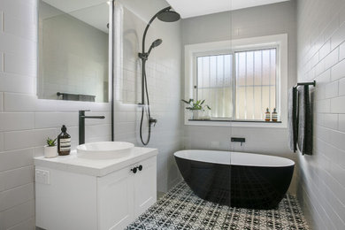This is an example of a mid-sized contemporary bathroom in Sydney with white cabinets, an open shower, gray tile, porcelain tile, white walls, porcelain floors, a vessel sink, engineered quartz benchtops, an open shower and white benchtops.