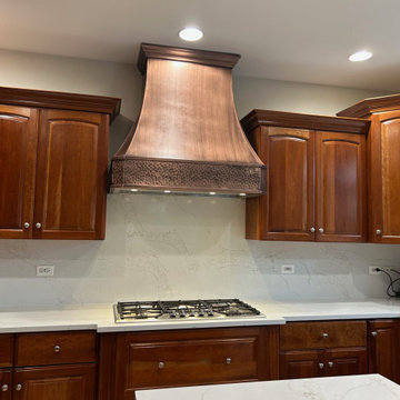 Custom copper kitchen hood paired with warm wood cabinetry and classic architect