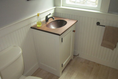 Small country powder room photo in Bridgeport with an undermount sink, white cabinets, wood countertops and recessed-panel cabinets