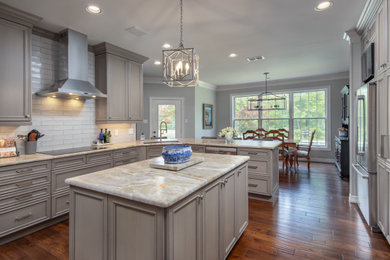 Example of a large transitional u-shaped medium tone wood floor and brown floor eat-in kitchen design in Austin with an undermount sink, recessed-panel cabinets, quartzite countertops, stainless steel appliances, an island, gray cabinets, gray backsplash, subway tile backsplash and gray countertops
