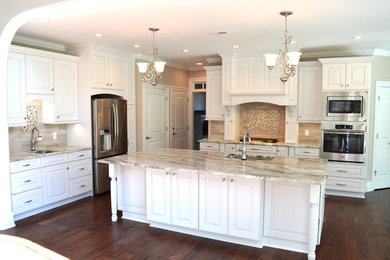 Open concept kitchen - mid-sized transitional l-shaped open concept kitchen idea in Wilmington with an undermount sink, raised-panel cabinets, white cabinets, quartzite countertops, beige backsplash, stainless steel appliances and an island