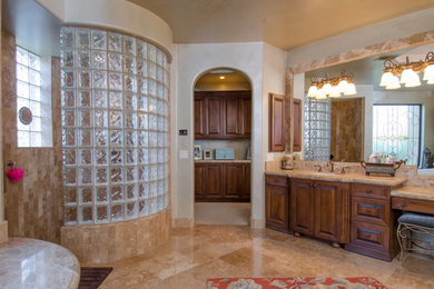 Elegant master beige tile and stone tile marble floor bathroom photo in Phoenix with an undermount sink, raised-panel cabinets, medium tone wood cabinets, marble countertops, a hot tub and multicolored walls