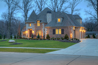 Inspiration for a huge 1950s brown three-story brick exterior home remodel in Cleveland with a hip roof