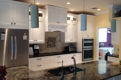 Mid-sized transitional travertine floor open concept kitchen photo in Other with an undermount sink, shaker cabinets, white cabinets, granite countertops, beige backsplash, stone tile backsplash, stainless steel appliances and an island