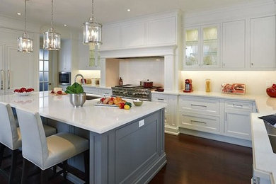 Large elegant u-shaped dark wood floor and brown floor kitchen photo in Miami with an undermount sink, beaded inset cabinets, white cabinets, solid surface countertops, white backsplash, stone slab backsplash, paneled appliances and an island