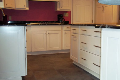 Example of a mid-sized transitional l-shaped slate floor and multicolored floor eat-in kitchen design in Other with an undermount sink, recessed-panel cabinets, white cabinets, granite countertops, pink backsplash, stainless steel appliances, an island and black countertops