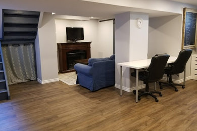 Basement in Toronto with grey walls, vinyl flooring and brown floors.