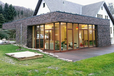 Mittelgroßes, Zweistöckiges Modernes Einfamilienhaus mit Steinfassade, roter Fassadenfarbe und Flachdach in Sonstige