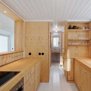 На фото: маленькая параллельная кухня-гостиная в скандинавском стиле с плоскими фасадами, светлыми деревянными фасадами, столешницей из дерева, деревянным полом, накладной раковиной и техникой под мебельный фасад без острова с