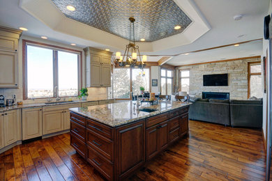 Inspiration for a mid-sized transitional medium tone wood floor eat-in kitchen remodel in Denver with an undermount sink, black cabinets, laminate countertops, beige backsplash, subway tile backsplash and stainless steel appliances