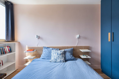 Diseño de dormitorio actual pequeño con paredes rosas, suelo de madera clara y suelo beige