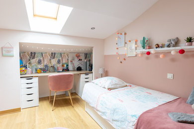 Diseño de dormitorio infantil actual de tamaño medio con paredes rosas, suelo de madera clara, suelo beige y papel pintado