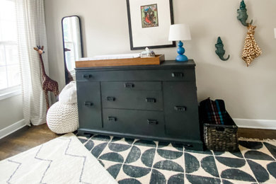 Example of a mid-sized eclectic gender-neutral medium tone wood floor nursery design in Atlanta with gray walls