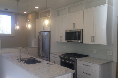 Enclosed kitchen - mid-sized transitional enclosed kitchen idea in New York with an undermount sink, shaker cabinets, white cabinets, marble countertops, gray backsplash, subway tile backsplash, stainless steel appliances and an island