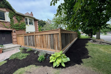 This is an example of a mid-sized traditional backyard brick and wood fence landscaping in Other.
