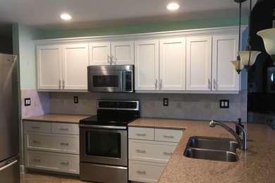Example of a l-shaped ceramic tile and beige floor enclosed kitchen design in Miami with an undermount sink, shaker cabinets, white cabinets, granite countertops, beige backsplash, stainless steel appliances, no island and beige countertops