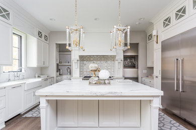 Inspiration for a large contemporary u-shaped medium tone wood floor and brown floor open concept kitchen remodel in Indianapolis with a farmhouse sink, shaker cabinets, white cabinets, marble countertops, white backsplash, stainless steel appliances and an island