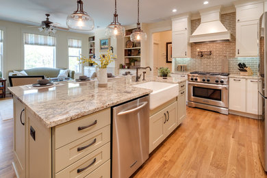 This is an example of a large traditional l-shaped open plan kitchen in Atlanta with a farmhouse sink, shaker cabinets, white cabinets, granite benchtops, subway tile splashback, stainless steel appliances, medium hardwood floors, with island, brown floor, beige benchtop and brown splashback.