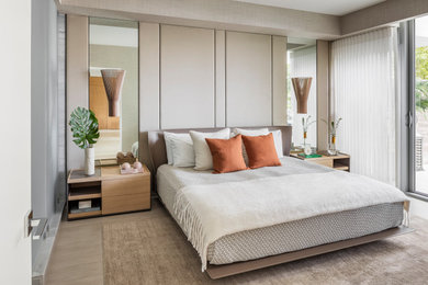Example of a mid-sized trendy master light wood floor and tray ceiling bedroom design in Miami with beige walls