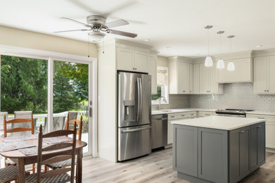 Mid-sized transitional l-shaped laminate floor and beige floor eat-in kitchen photo in Other with an undermount sink, shaker cabinets, beige cabinets, quartz countertops, beige backsplash, glass tile backsplash, stainless steel appliances, an island and beige countertops