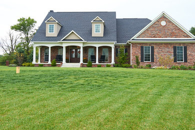 Inspiration for a large timeless red two-story brick exterior home remodel in Indianapolis with a shingle roof