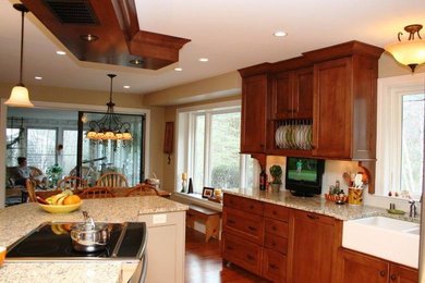 Example of a mid-sized classic l-shaped medium tone wood floor eat-in kitchen design in Milwaukee with a farmhouse sink, raised-panel cabinets, dark wood cabinets, granite countertops, white backsplash, ceramic backsplash, stainless steel appliances and an island